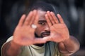 One handsome young trendy african american man using his two hands to frame his face for a photograph in a city. Serious