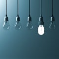 One hanging energy saving light bulb glowing different stand out from unlit incandescent bulbs