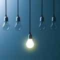 One hanging light bulb glowing different and standing out from unlit incandescent bulbs Royalty Free Stock Photo