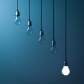 One hanging light bulb glowing different and standing out from unlit incandescent bulbs Royalty Free Stock Photo