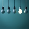 One hanging light bulb glowing different standing out from unlit incandescent bulbs with reflection on dark green background Royalty Free Stock Photo