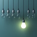 One hanging light bulb glowing different and standing out from unlit incandescent bulbs Royalty Free Stock Photo
