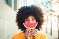 One happy and beauty cheerful woman holding a small watermelon covering her mouth. African or American girl having fun and Royalty Free Stock Photo