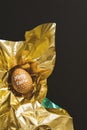 One happy easter written egg wrapped in metallic shiny gold paper on black background