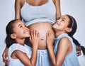 One happy family. two cheerful little girls standing next to their pregnant mother at home during the day. Royalty Free Stock Photo