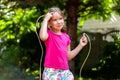 One happy little girl, child with a jumping rope in the garden outside, kid holding a skipping rope smiling outdoors, closeup Royalty Free Stock Photo