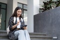 One happy student walking and using smart phone on line in the street at sunset with a warm back light Royalty Free Stock Photo