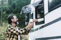 One happy traveler man receive a coffee cup from a woman. Couple enjoy camper van travel destination at mountains with green trees Royalty Free Stock Photo