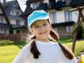One happy young elementary school age child, cheerful girl smiling in the sun, simple outdoors portrait, kid in a baseball cap Royalty Free Stock Photo