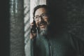 One happy young mature man speaking at the phone smiling and having fun at home near the window. Concept of people and mobile cell Royalty Free Stock Photo