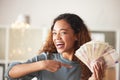 One happy young mixed race woman feeling excited and using hand gesture to point at money. Hispanic woman holding euro