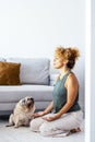 One healthy adult woman at home doing meditation exercise in yoga oriental zen position with her best friend dog pug sitting near