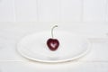 One heart-shaped cherry on a white plate. Ripe fresh juicy berry on a white background. Fruit background. valentine Royalty Free Stock Photo