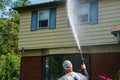 One heavy overweight Caucasian man spraying water solution on the front of a house as part of his pressure washing service Royalty Free Stock Photo