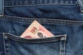 One hundred baht banknote of Thailand in the back pocket of jeans