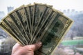 One hundred dollar banknotes in man hand with cityscape in the background.