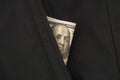 A one hundred dollar bill in the pocket of a black jacket Royalty Free Stock Photo