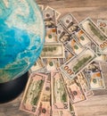 One hundred dollar bills as background for the geographic globe.