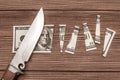 A one hundred dollar denomination cut into pieces using a knife against the background