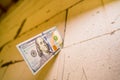 One hundred dollar paper cash bill sticking out of an aerated concrete brick wall close-up against a blurred background. Bare