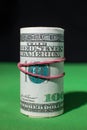 One hundred Dollar roll tightened red rubber band Royalty Free Stock Photo