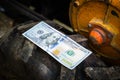 One hundred dollars close-up lie on the wheel of a walk-behind tractor. The money lies on a tire with a large tread in the mud. Royalty Free Stock Photo