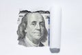 One hundred dollars through torn white paper. Royalty Free Stock Photo
