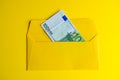 Euro banknote in envelope on yellow background.