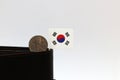 One hundred Korean won coin on obverse, KRW and mini South Korea flag stick on the black wallet with white background