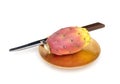 One Indian aka Barbary fig, Opuntia ficus-indica on gold colour plate with knife on white. Aka Prickly pear Tuna fruit.