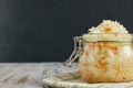 One jar of sauerkraut and carrots in its own juice with spices on a light, white wooden table, black background, horizontal view Royalty Free Stock Photo