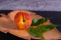 One juicy and ripe peach lies in a carved wooden plate Royalty Free Stock Photo