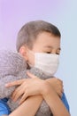 One kid, a boy in a white medical mask on his face, hugs a teddy bear tightly, the concept of health, treatment of diseases, Royalty Free Stock Photo