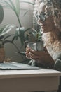 One lady using laptop at home drinking tea or coffee in indoor leisure activity online. Pretty woman working on computer and Royalty Free Stock Photo