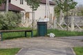 One large bin full of rubbish stands in the green grass near the gray sidewalk Royalty Free Stock Photo