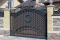 One large brown metal gate with a black wrought iron pattern on a brick wall Royalty Free Stock Photo