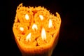 One large candle made of beeswax on a black background, top view of seven small candles of beeswax in one, fire is burning.fire tr