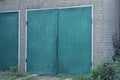 One large facade of a gray brick garage with green iron gates