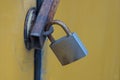 One large gray padlock hanging on a yellow iron wall