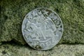 Large old silver medieval coin near the stone wall