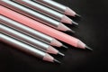 lead pink pencil different from others silver pencils on a black background Royalty Free Stock Photo