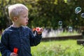 One Little boy blows soap bubbles in the garden on a summer day Royalty Free Stock Photo