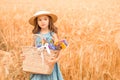 One little cute girl in a straw hat and a blue dress among a golden wheat field Royalty Free Stock Photo