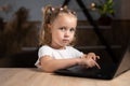 one little girl is sitting at a laptop in the evening and is typing. Portrait of a preschool child. Royalty Free Stock Photo