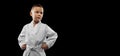 One little kid, boy, taekwondo athlete wearing white dobok isolated over dark background. Concept of sport, education