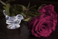 One little transparent bird decoration with two roses on the table.Dark  background. Royalty Free Stock Photo