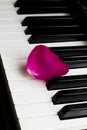 One lone rose petal of pink scarlet lies on black and white piano keys. romantic music, lightness and romance of relaxation and Royalty Free Stock Photo
