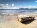 One lone stone in sand of beach close to lake water. Detail