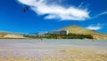 One lonely kite surfer on endless wide sand beach in shallow water ebb stream, seaside hotel resort, dry hills, blue sky - Playa Royalty Free Stock Photo