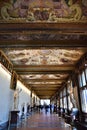 One of the long, full of works and with a completely frescoed ceiling, corridors of the Uffizi museum in Florence.